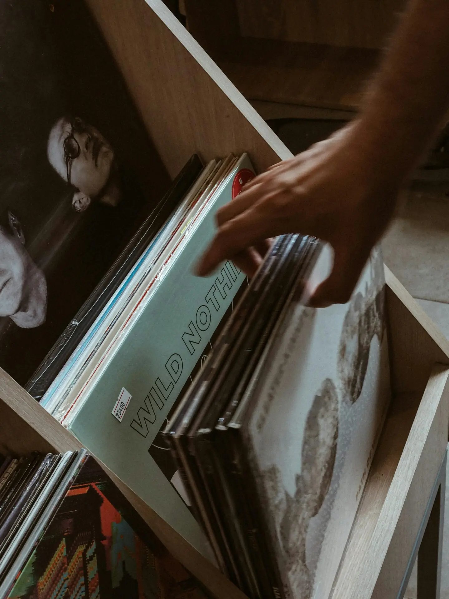Close-up of a hand browsing vintage vinyl records in a store setting.
